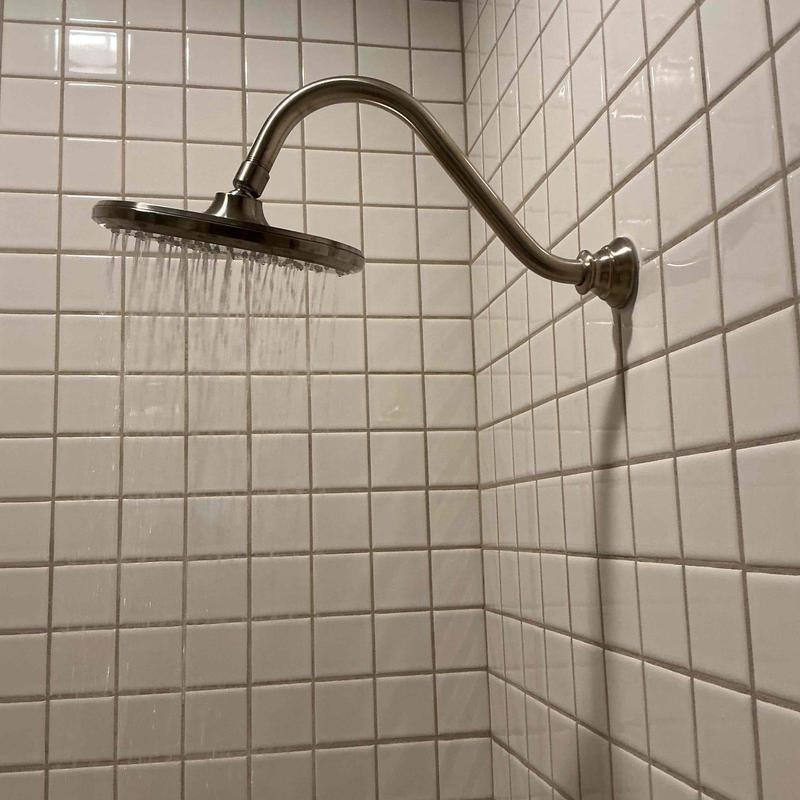 Shower head with water flowing in tiled shower