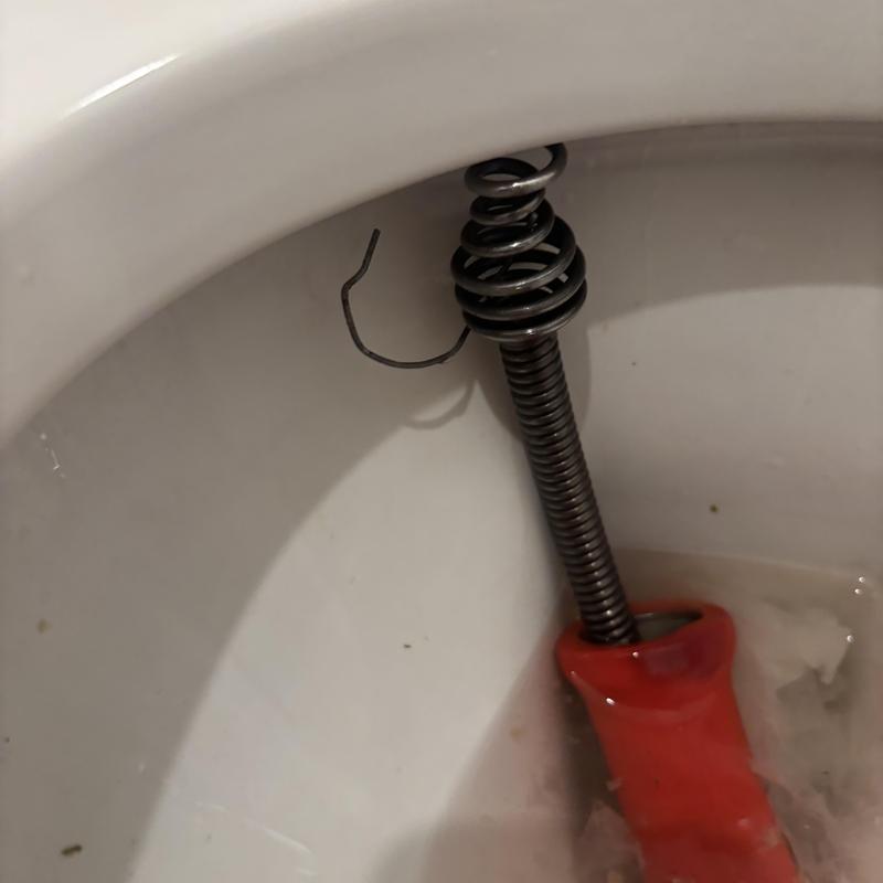 Toilet clog with wire removal tool inside bowl Toilet clog with wire removal tool inside bowl