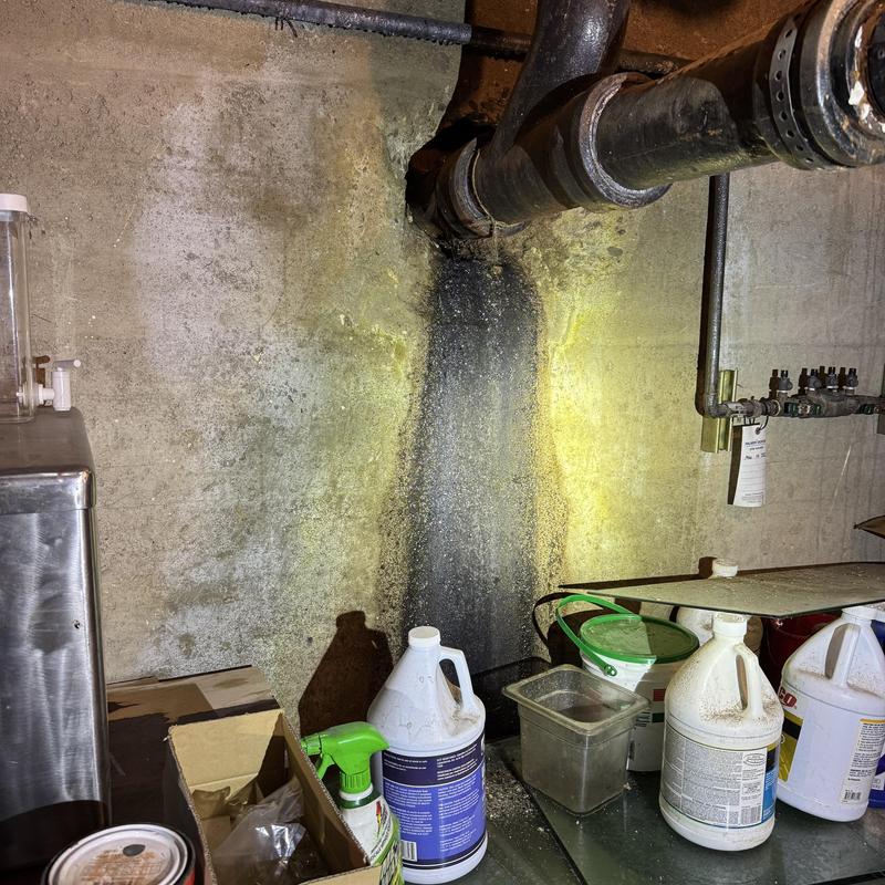 Sewer drain pipe with leak stain on basement wall Sewer drain pipe with leak stain on basement wall