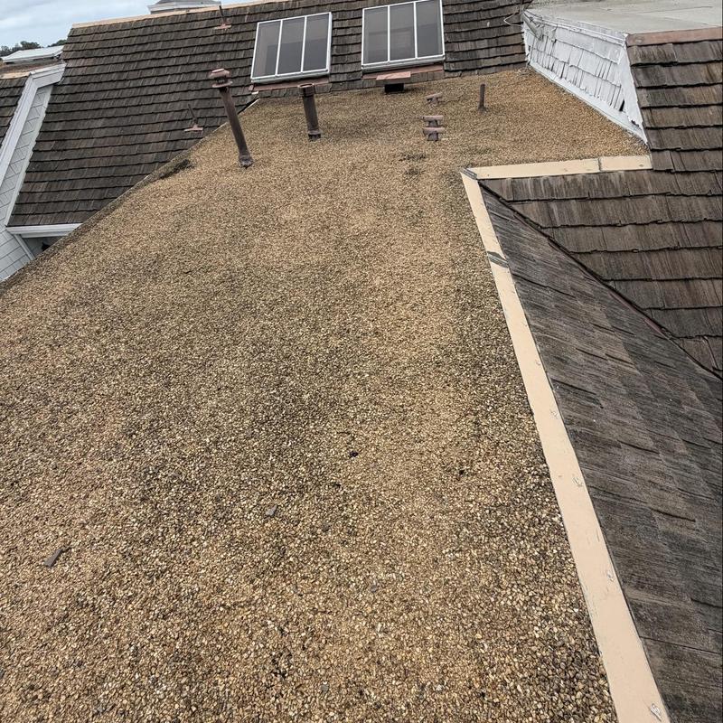 Flat gravel roof with vent pipes and wood shingles Flat gravel roof with vent pipes and wood shingles