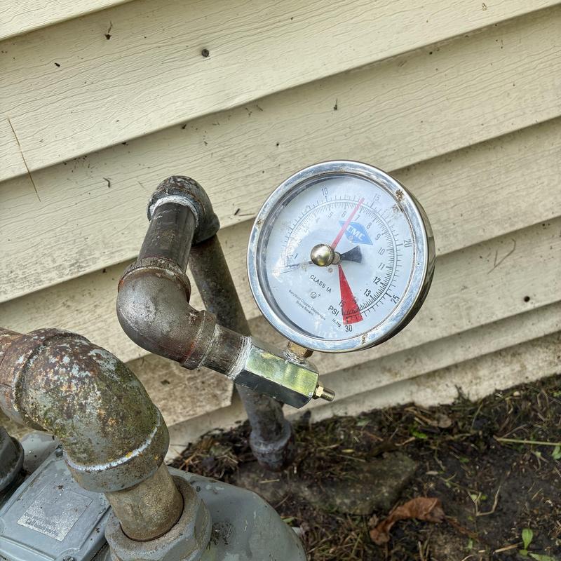 Gas pressure gauge on outdoor piping near house siding Gas pressure gauge on outdoor piping near house siding