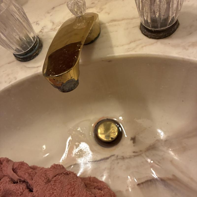 Bathroom faucet with worn brass finish on sink Bathroom faucet with worn brass finish on sink