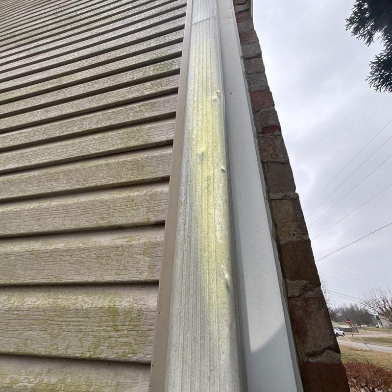 Metal downspout with dents on house exterior siding