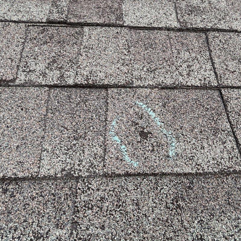 Roof shingles with hail damage marked for repair