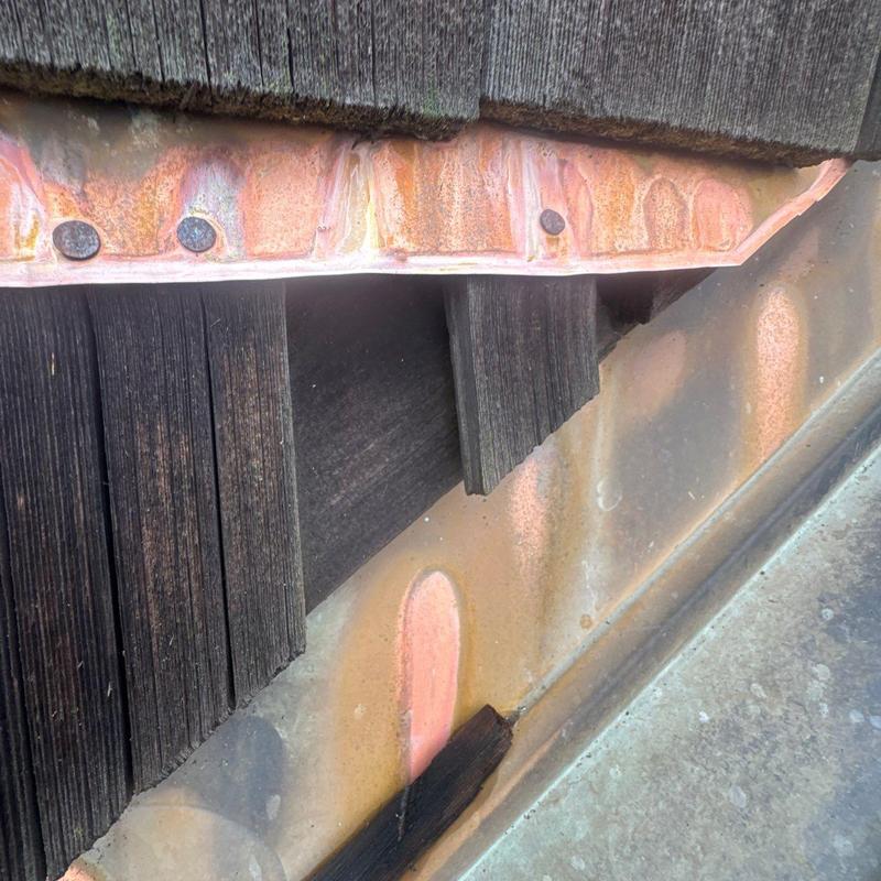 Copper flashing with nailed weathered wood shingles close-up