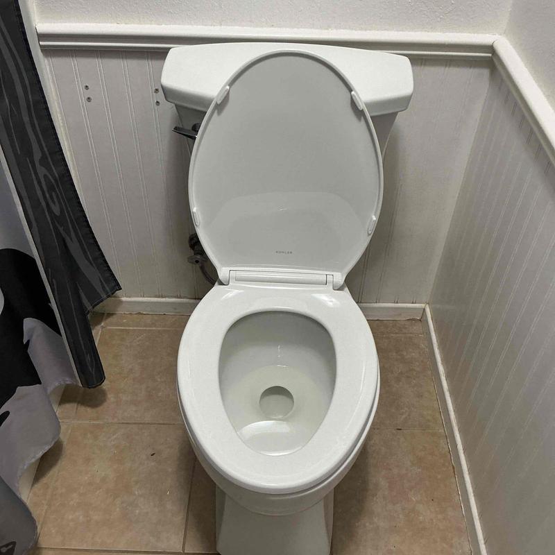 Kohler toilet with open lid in bathroom corner