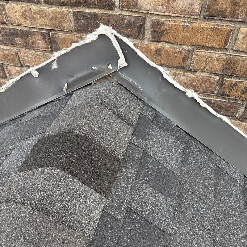 Roof flashing and shingle hail damage near brick wall