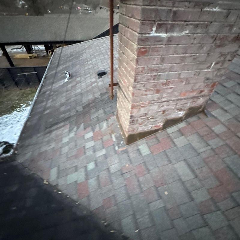 Asphalt shingle roof around brick chimney inspection