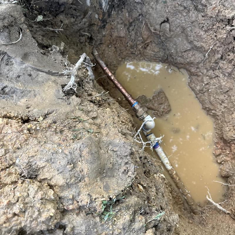 Water main pipe with valve in muddy excavation site Water main pipe with valve in muddy excavation site