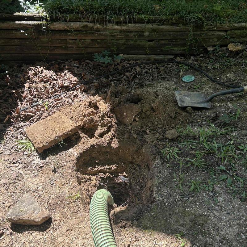 Septic tank riser with green pump hose outdoors Septic tank riser with green pump hose outdoors