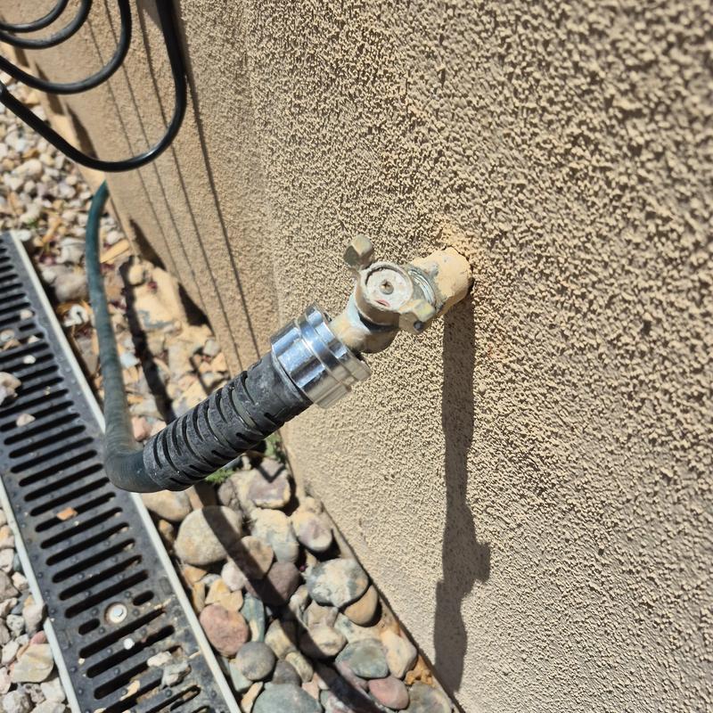 Hose bib with attached garden hose and drainage grate