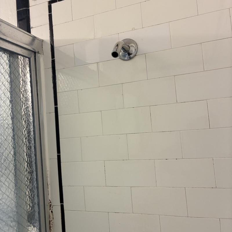 Shower arm pipe installed on tiled bathroom wall