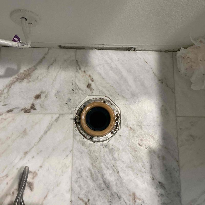 Toilet flange with new wax ring installed on marble floor