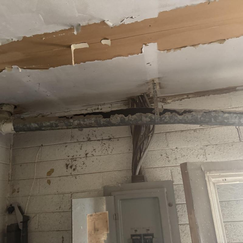 Corroded gas exhaust pipe above electrical panel