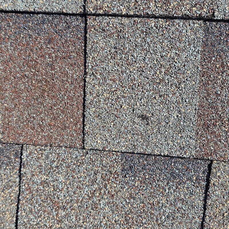 Asphalt roof shingles with visible hail damage close-up