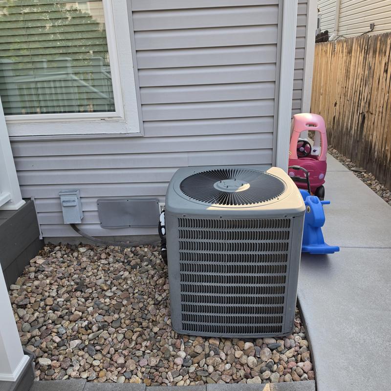 Air conditioner unit outside residential home with toys nearby