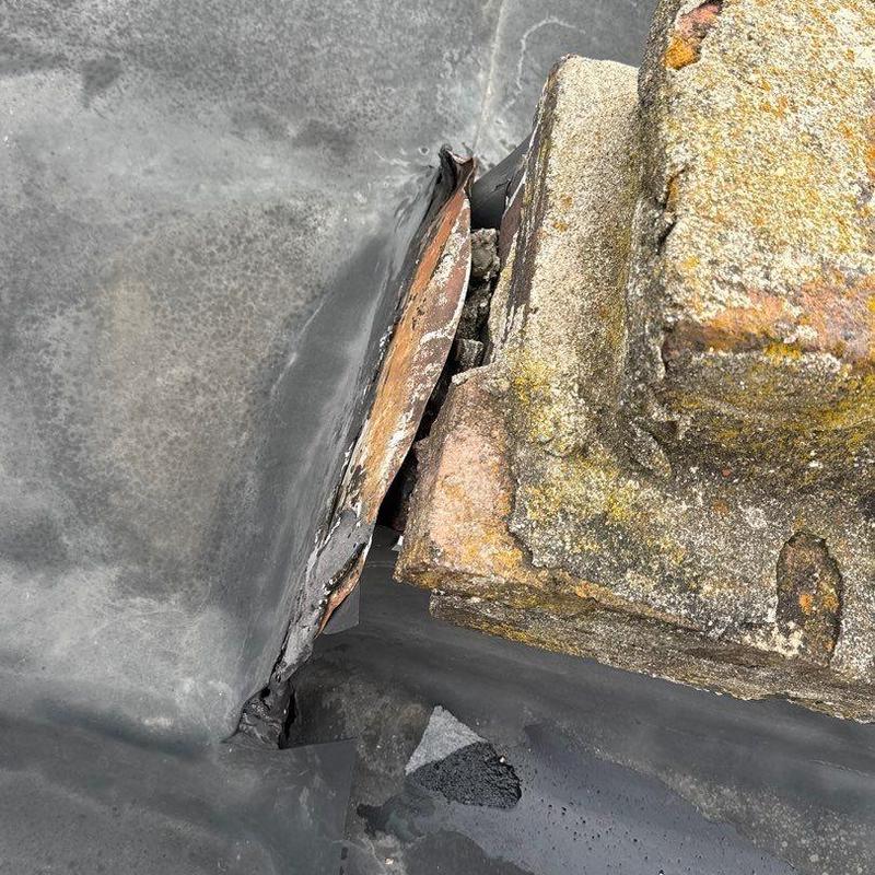 Roof flashing with hail damage near brick structure