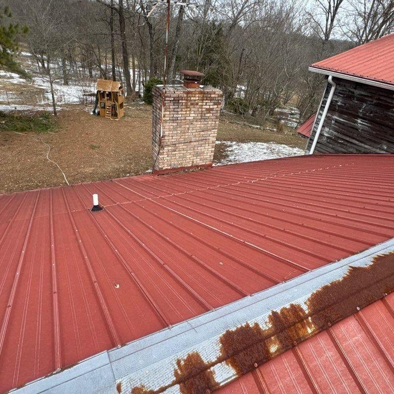 Metal roofing with rusted ridge cap and chimney nearby