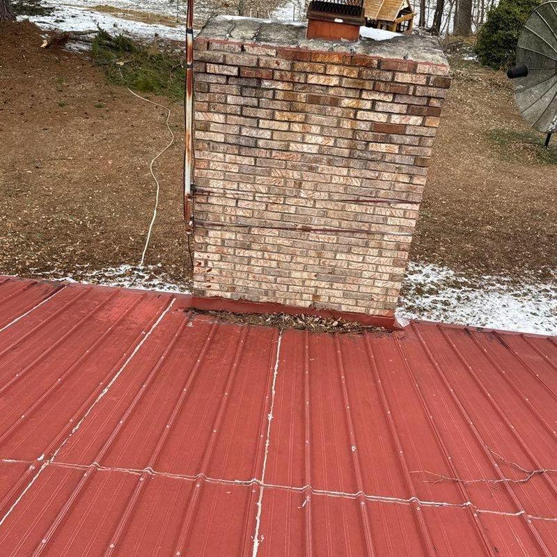 Brick chimney flashing on red metal roof