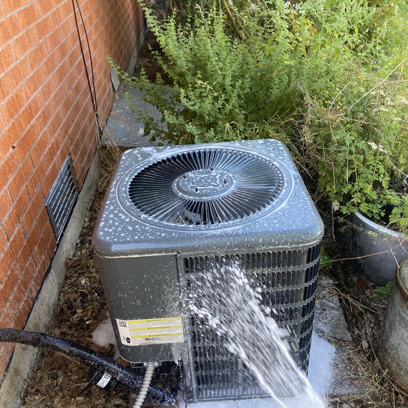 Condenser compressor unit being cleaned with water spray Condenser compressor unit being cleaned with water spray