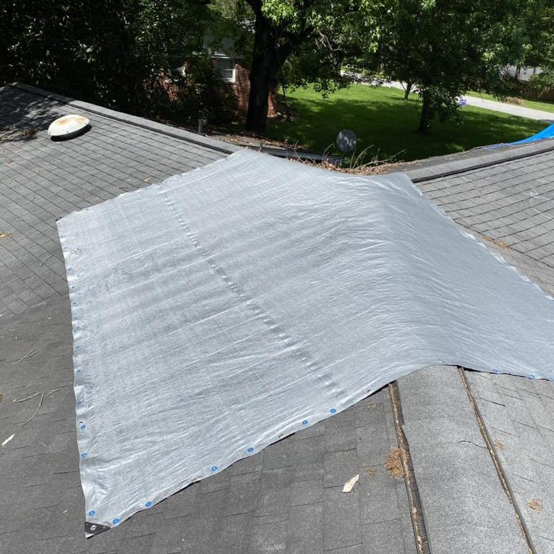Roof tarp covering damaged shingles after tree limb impact