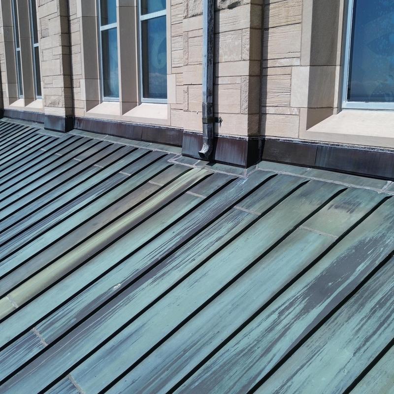 Copper flashing on metal roof near building windows