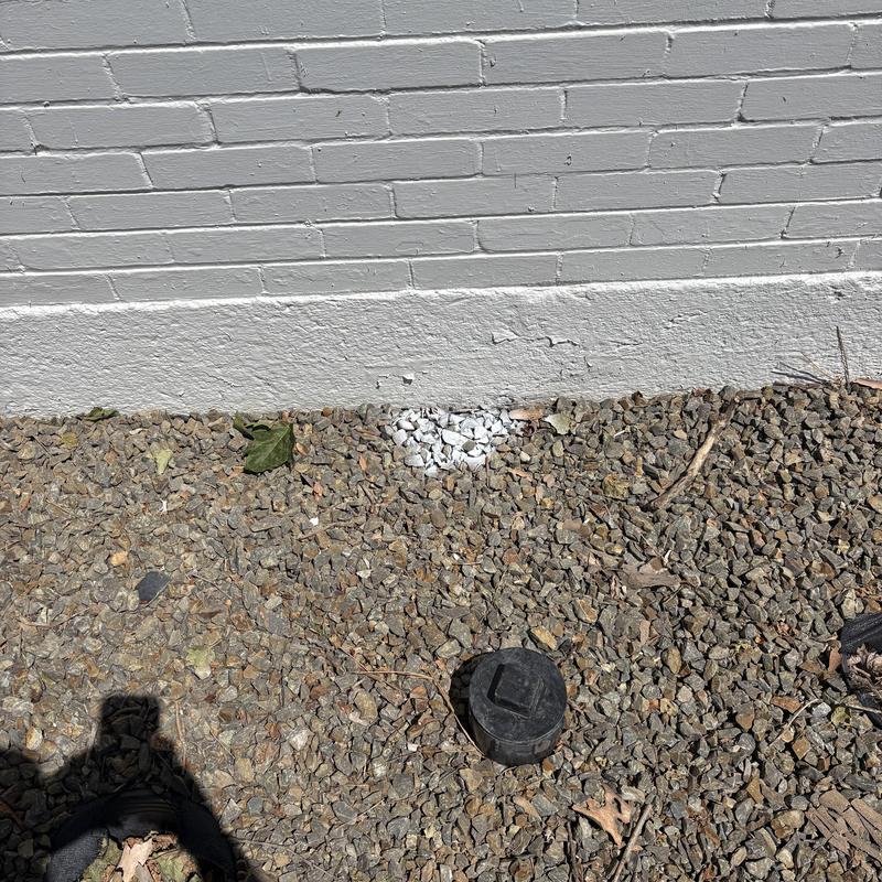 Sewer line cleanout cap among gravel near building wall Sewer line cleanout cap among gravel near building wall