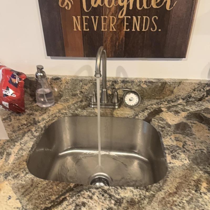 Kitchen sink faucet with running water on granite countertop Kitchen sink faucet with running water on granite countertop