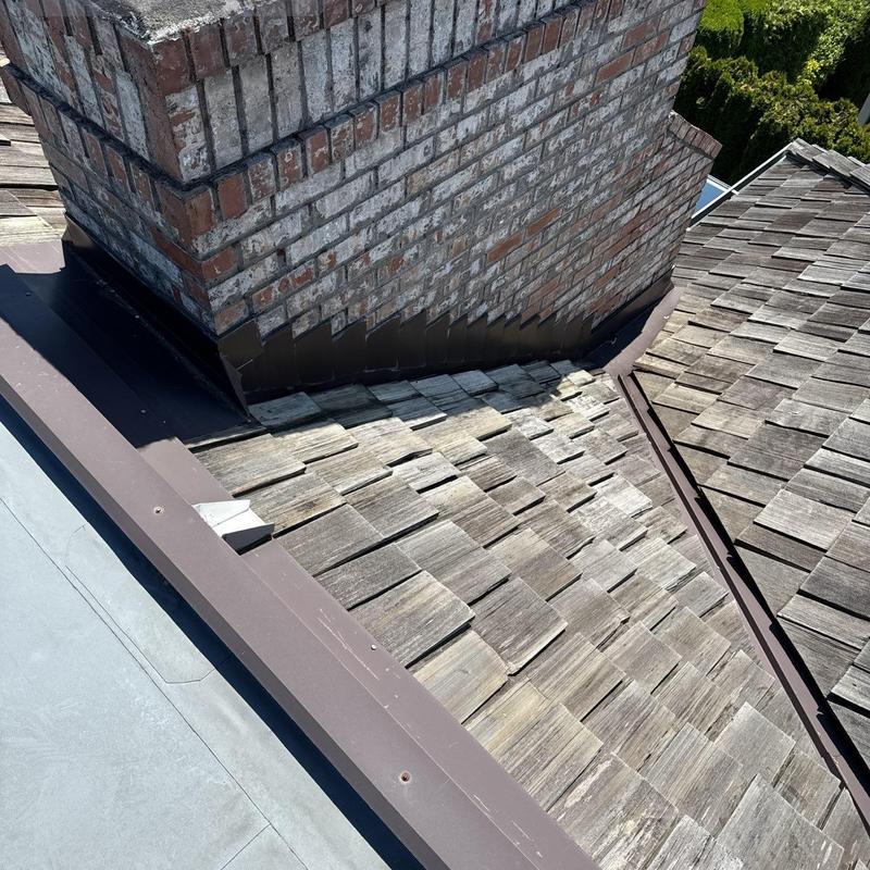 Wood shingle roof flashing around brick chimney inspection
