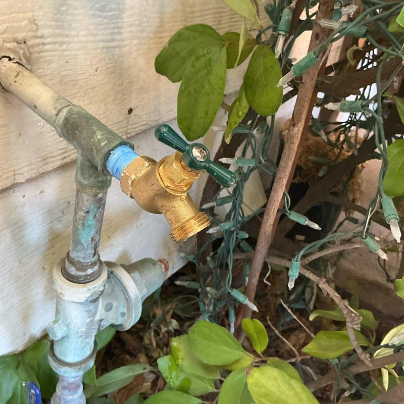 12-port brass hose bib with green handle outdoors