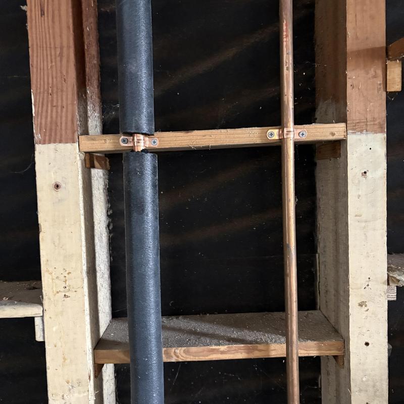 Copper and insulated drain pipes installed in wall studs
