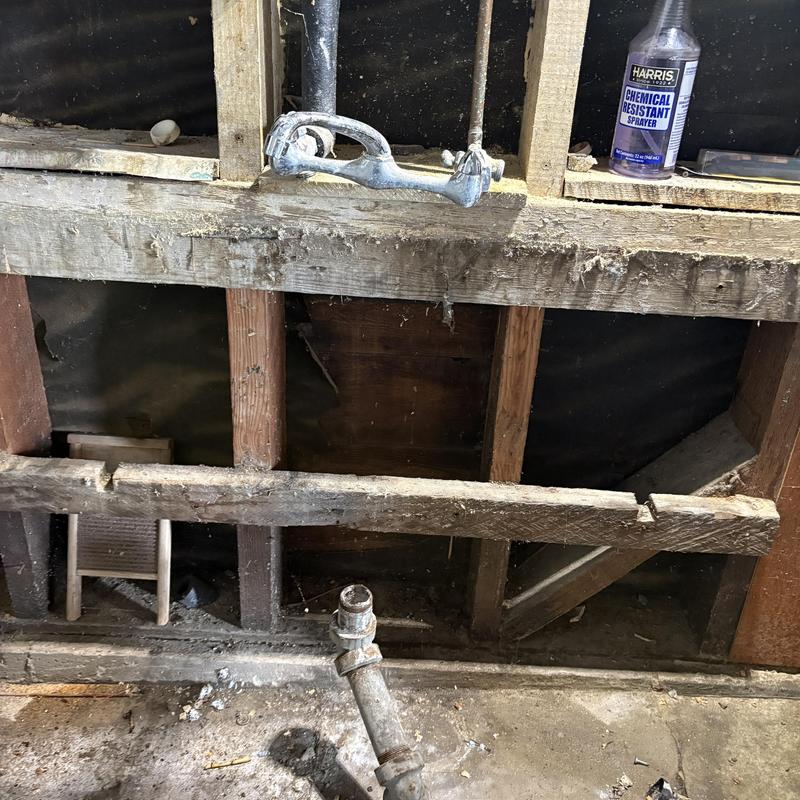 Exposed kitchen sink plumbing with faucet and pipes