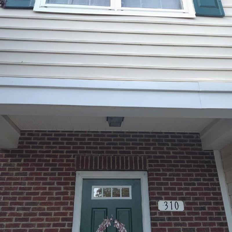 Metal fascia and vinyl siding above brick entry door