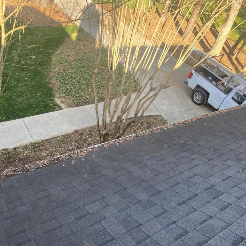 Asphalt shingle roof inspection with white work truck nearby