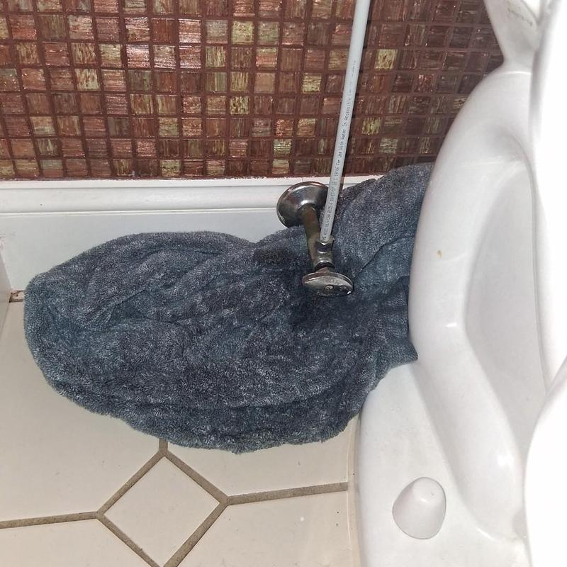 Toilet stop valve with towel on tile floor