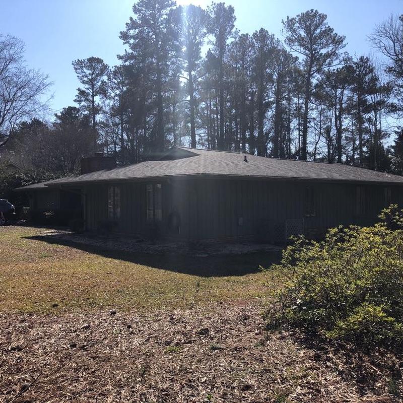 Gutters and skylight on residential roof with surrounding trees