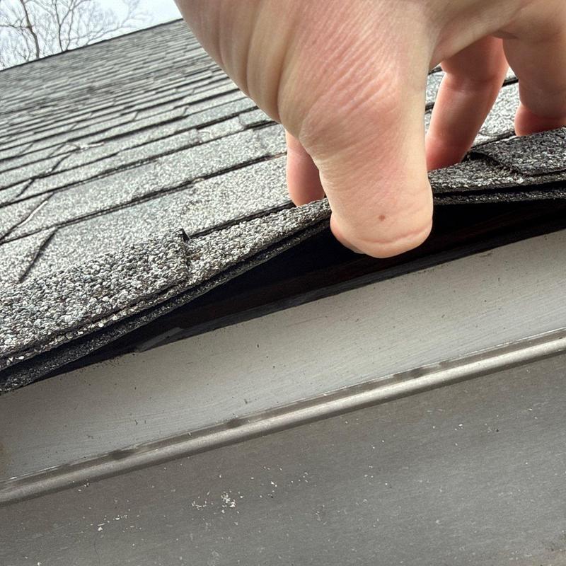 Asphalt roof shingle lifting during hail damage inspection