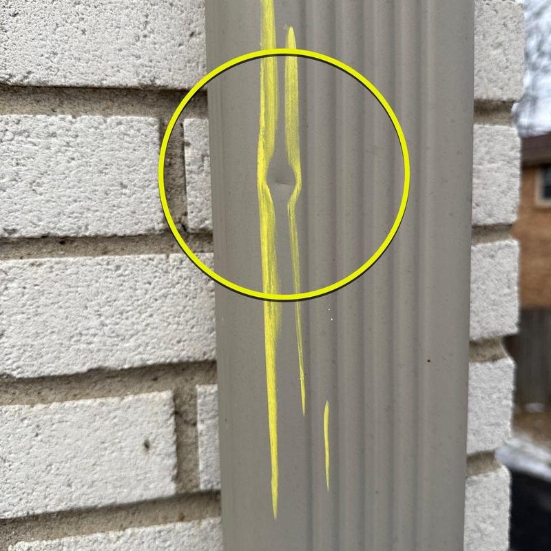 Downspout dent marked with yellow highlighting on exterior