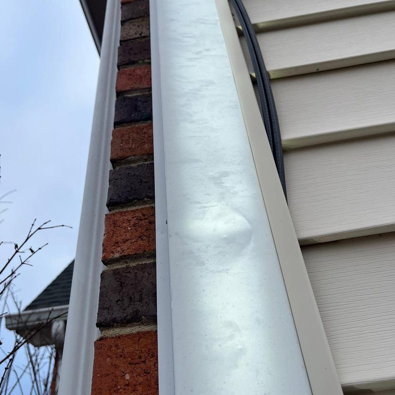 Metal flashing with visible hail damage dents on house exterior