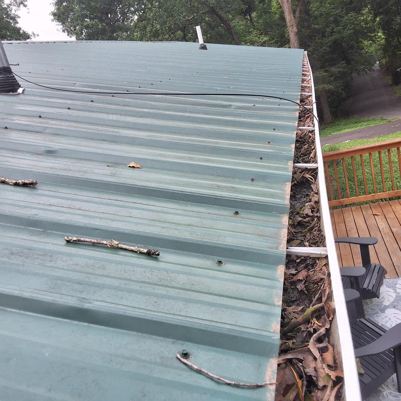 Metal roof with clogged gutter and debris buildup