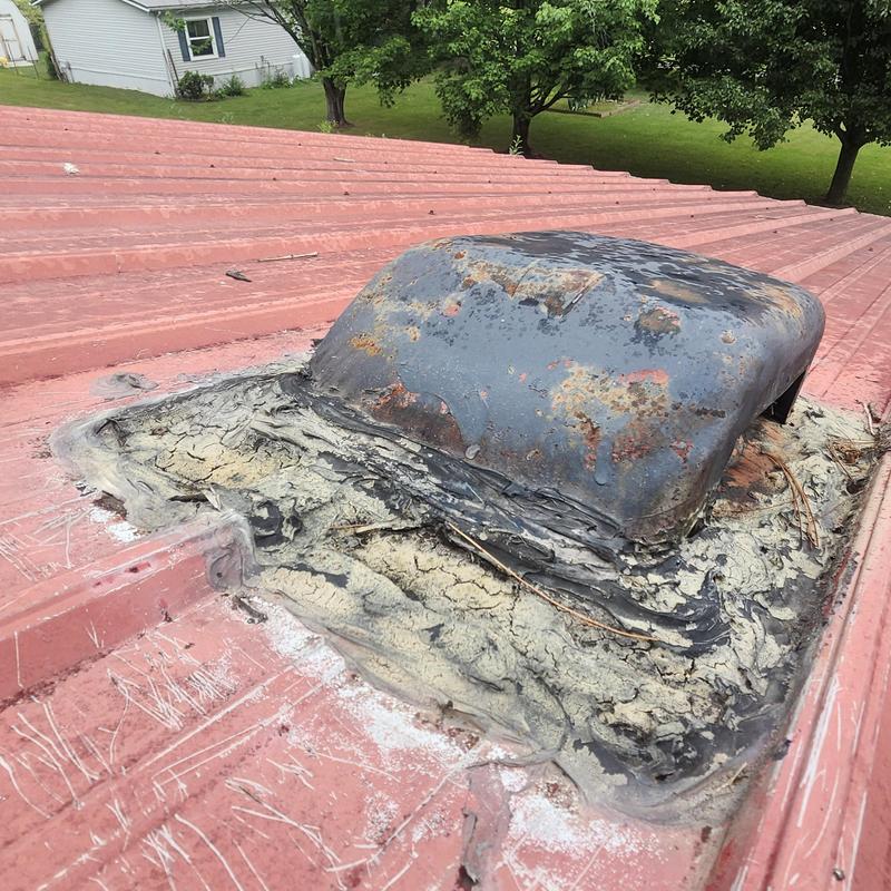 Metal roof vent with old sealant and rust damage