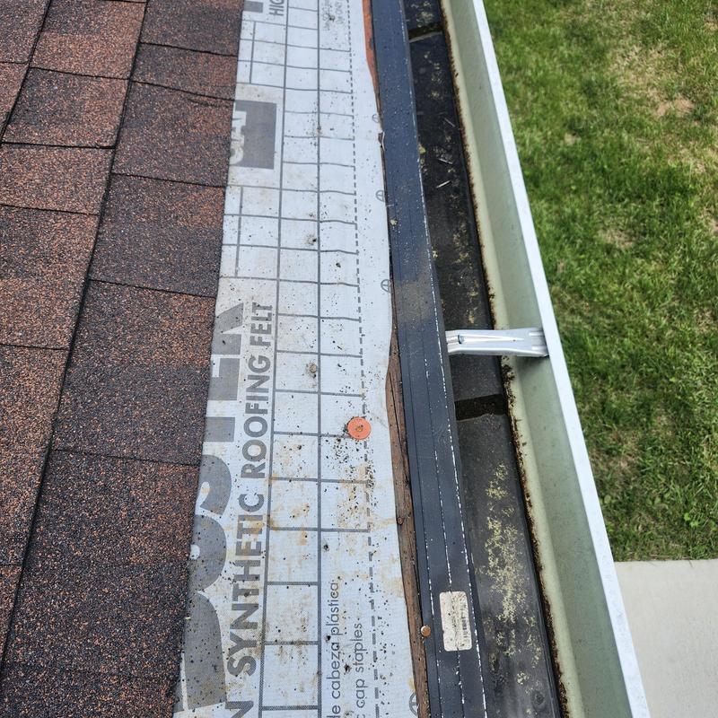 Synthetic roofing felt under damaged shingles near gutter