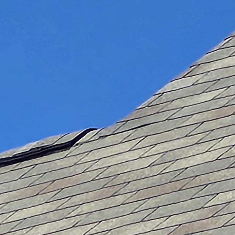 Asphalt shingles with visible gap near ridge line