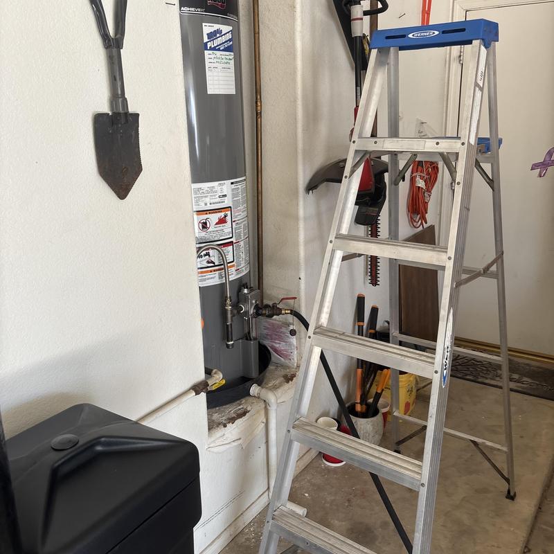 Water heater installation area with ladder and tools