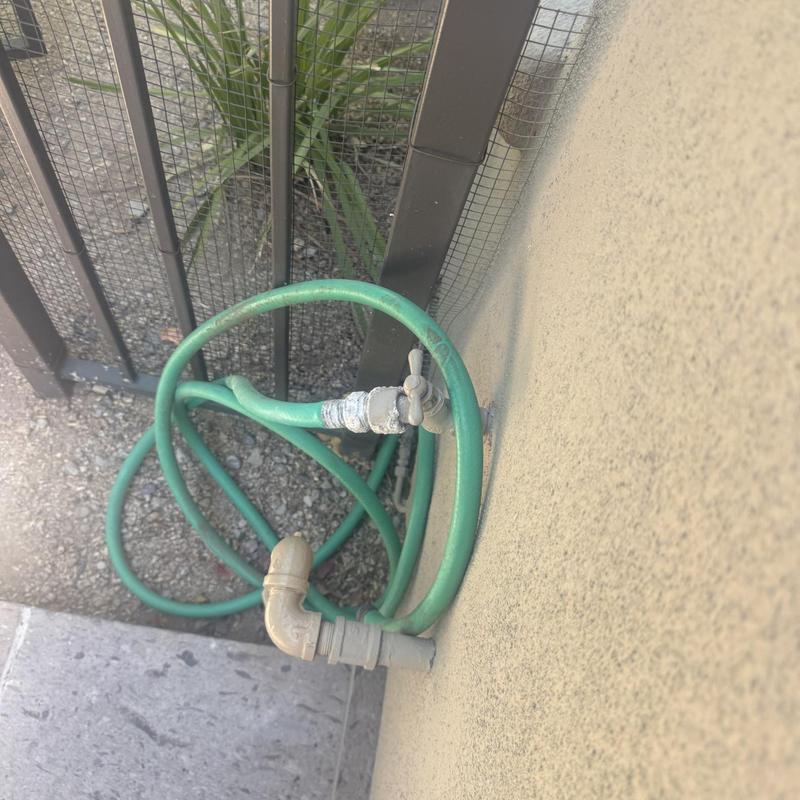 Outdoor hose bib with green garden hose attached