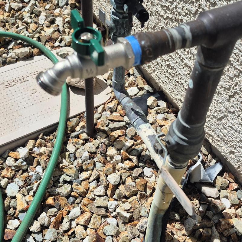 Outdoor hose bib with green handle and hose attached