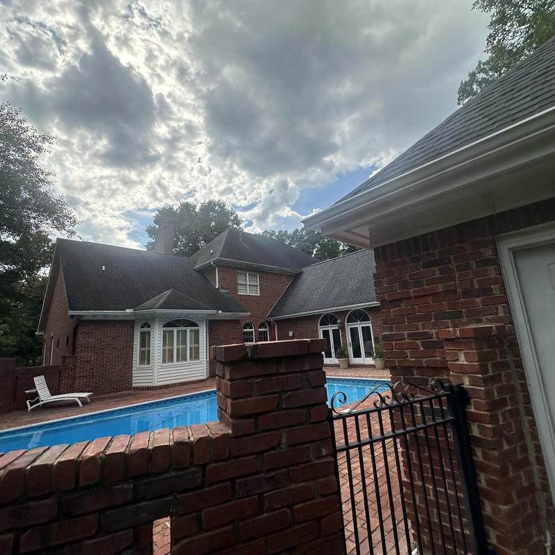 Residential asphalt shingle roof over brick house with pool
