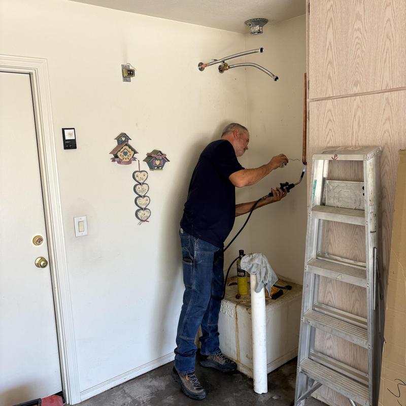 Gas water heater installation with plumber in garage