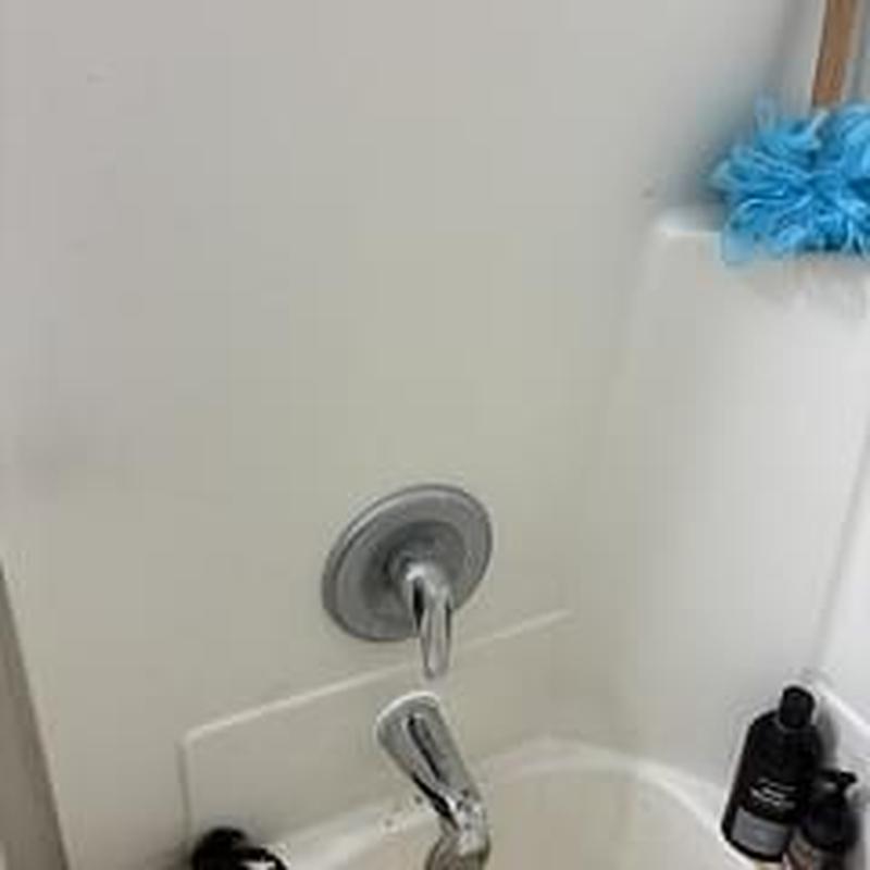 Diverter spout on bathtub with fixtures and cleaning items
