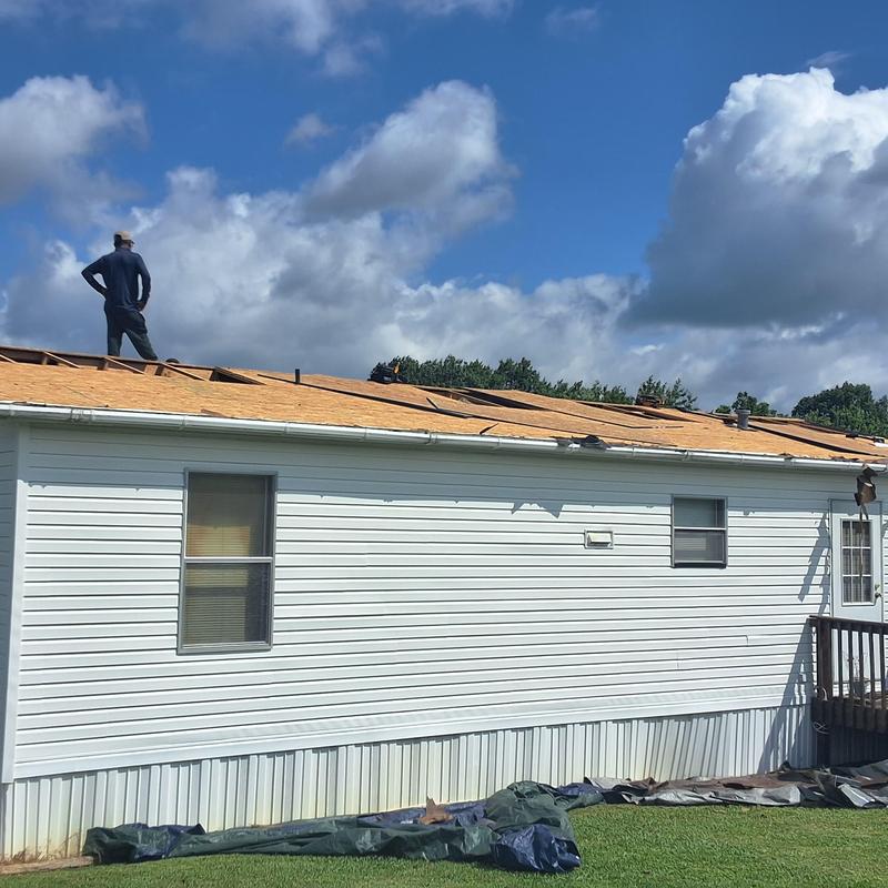 Wood roof sheathing installation on white mobile home